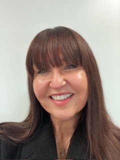 Nicky Denegri, smiling therapist with long brown hair and black top. 